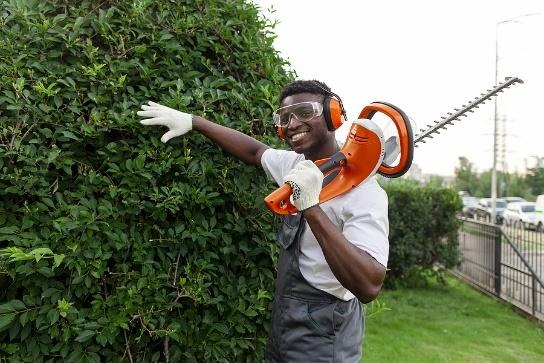 A Black Botlebembali landscaping team member maintaining a hedge